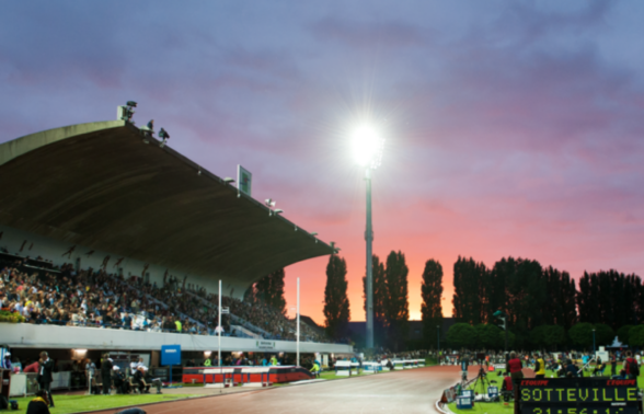 Photo de nuit de la piste d'athlétisme qui est surplombée par les gradins du stade
