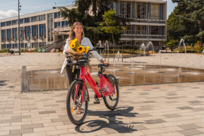 Une femme marche a côté de son Lovélo avec un bouquet de tournesol sur la place de l'Hôtel de ville - Agrandir l'image, fenêtre modale