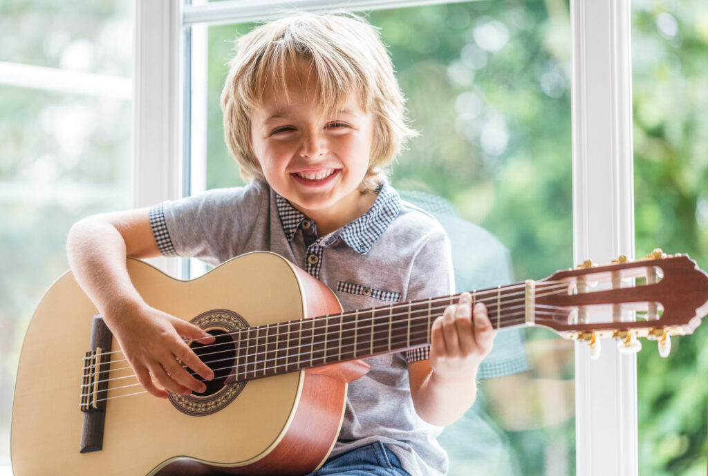 Un petit garçon souriant qui joue de la guitare