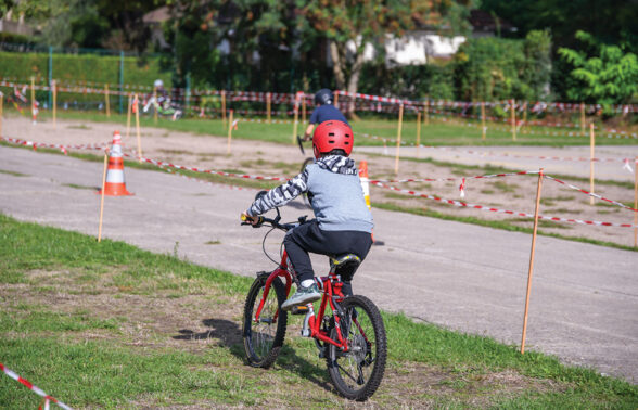 un enfant avec un casque rouge fait du vélo