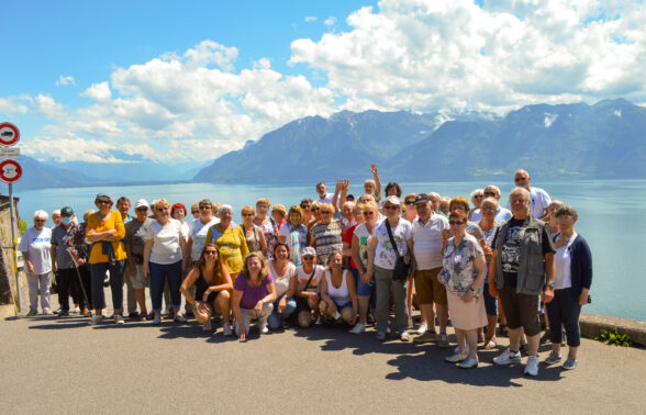 Un groupe de seniors prend la pose pour une photo de vacances avec les montagnes et un lac en arrière-plan